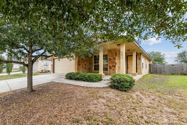 view of front of property with a garage, driveway, stone siding, and fence