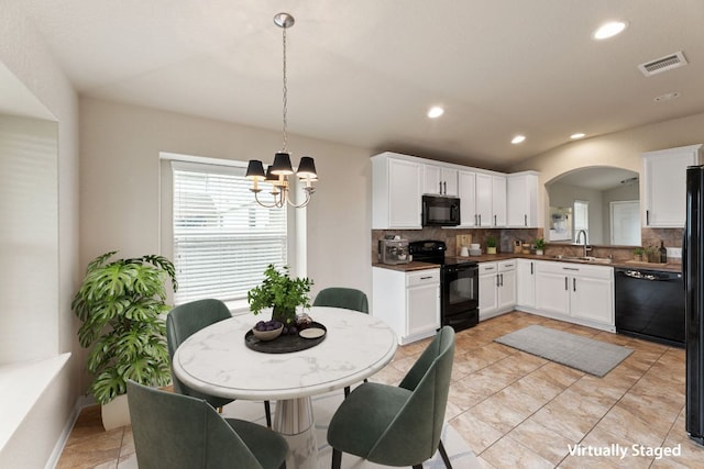 kitchen featuring visible vents, decorative backsplash, a sink, black appliances, and a wealth of natural light