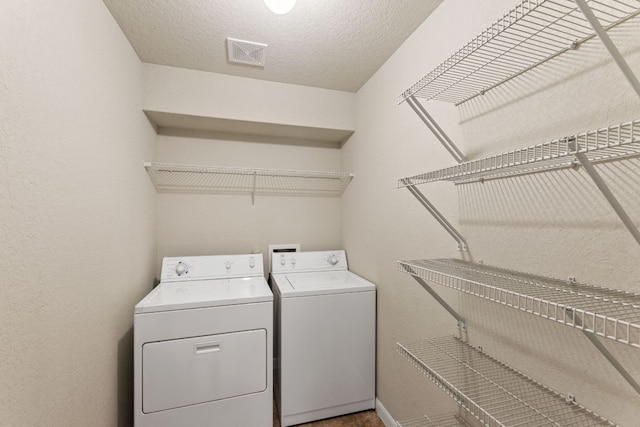 washroom with laundry area, visible vents, a textured ceiling, and washing machine and clothes dryer