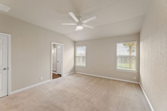 unfurnished bedroom featuring carpet floors, lofted ceiling, visible vents, and multiple windows