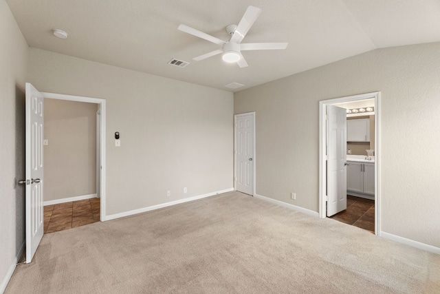 unfurnished bedroom featuring lofted ceiling, visible vents, carpet flooring, connected bathroom, and baseboards