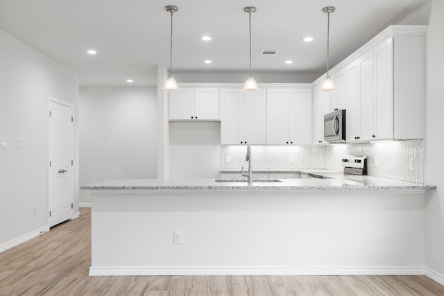 kitchen featuring sink, white cabinets, hanging light fixtures, stove, and light stone counters