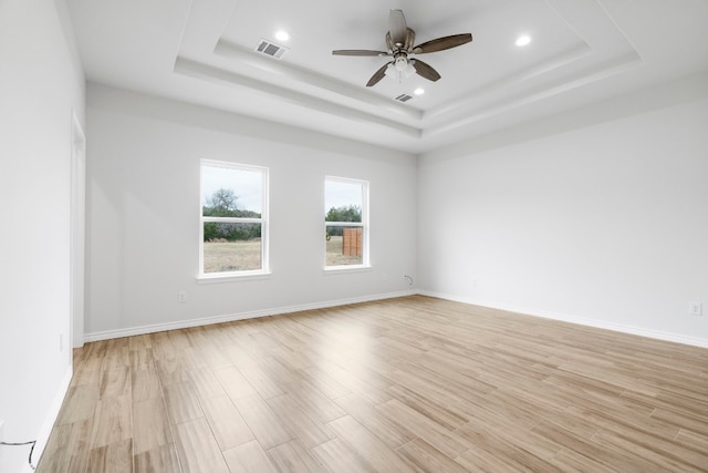 spare room featuring ceiling fan, a raised ceiling, and light hardwood / wood-style floors