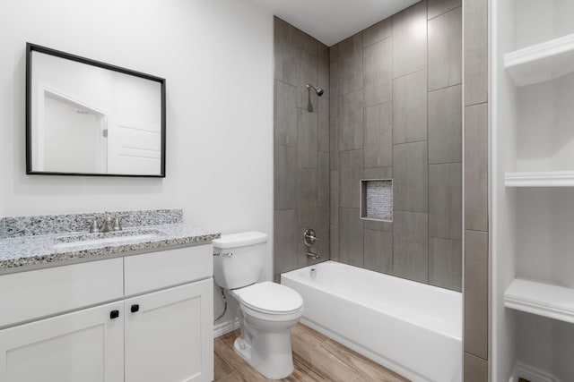 full bathroom featuring tiled shower / bath, hardwood / wood-style floors, vanity, and toilet