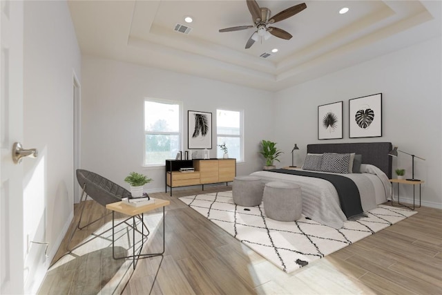 bedroom with a tray ceiling and light hardwood / wood-style floors