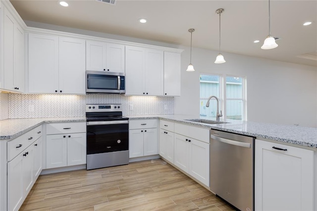 kitchen featuring stainless steel appliances, sink, pendant lighting, and white cabinets