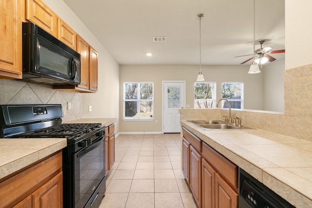 kitchen featuring light tile patterned floors, a healthy amount of sunlight, sink, and black appliances