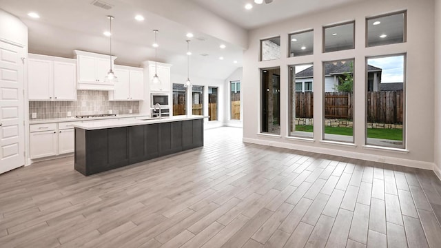 667 Bay Breeze Dr, Kyle, TX 78640 - kitchen featuring stainless steel gas stovetop, light countertops, white cabinetry, a center island with sink, and decorative backsplash