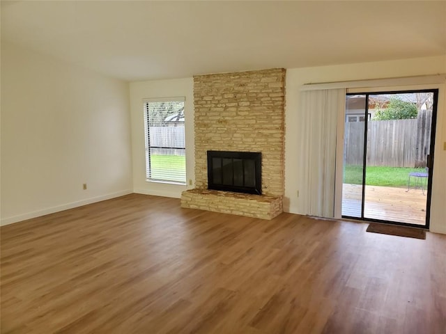 unfurnished living room featuring baseboards, wood finished floors, and a fireplace