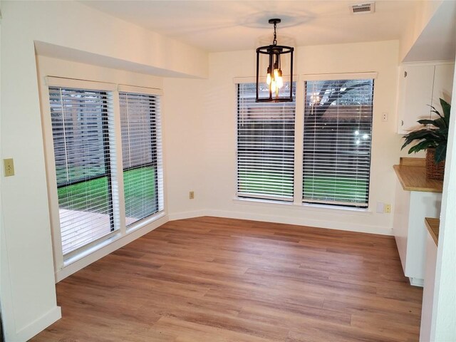 unfurnished dining area featuring wood-type flooring and an inviting chandelier