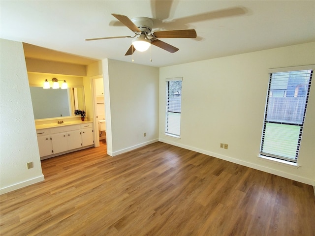 unfurnished bedroom with connected bathroom, sink, ceiling fan, and light wood-type flooring