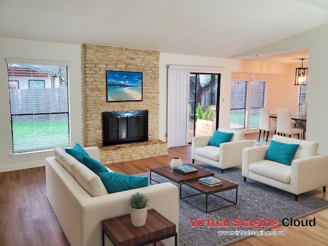 living room featuring a stone fireplace, vaulted ceiling, and hardwood / wood-style flooring