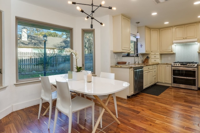 kitchen with hanging light fixtures, wood-type flooring, appliances with stainless steel finishes, and cream cabinets