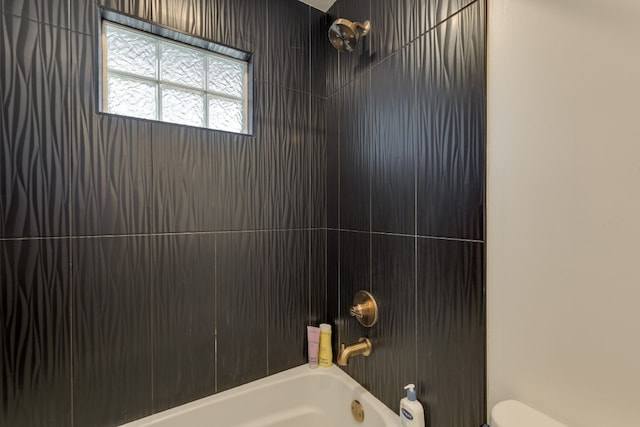 bathroom featuring tiled shower / bath combo and toilet