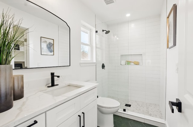 bathroom featuring vanity, tile patterned floors, toilet, and tiled shower