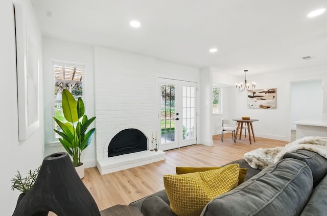 living room featuring french doors, a fireplace, a chandelier, and hardwood / wood-style floors