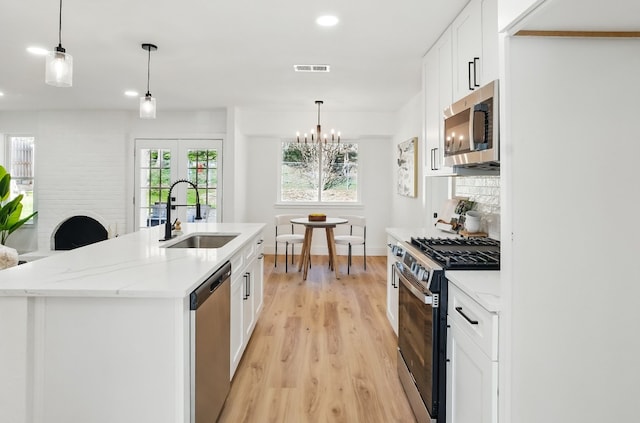 kitchen with white cabinetry, sink, a kitchen island with sink, and appliances with stainless steel finishes