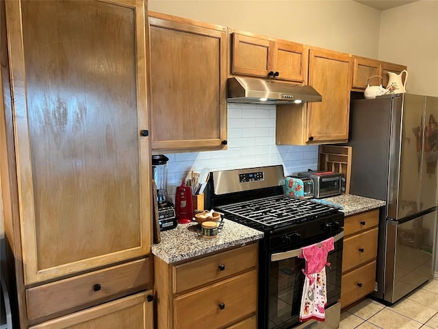 kitchen featuring stainless steel appliances, light tile patterned flooring, light stone counters, and decorative backsplash