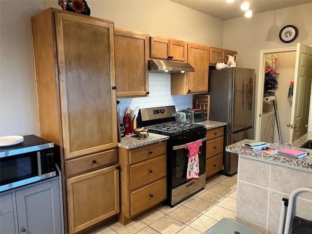 kitchen featuring tasteful backsplash, stainless steel appliances, light tile patterned flooring, and light stone counters