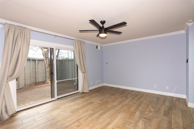 spare room featuring wood finished floors, ceiling fan, baseboards, ornamental molding, and visible vents