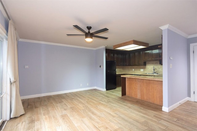 kitchen with sink, light hardwood / wood-style flooring, ornamental molding, black fridge, and decorative backsplash