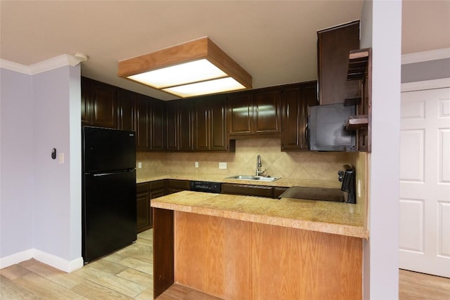 kitchen featuring a sink, black appliances, light wood-style flooring, backsplash, and a peninsula