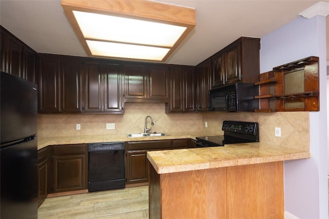 kitchen featuring open shelves, a sink, black appliances, light countertops, and a peninsula