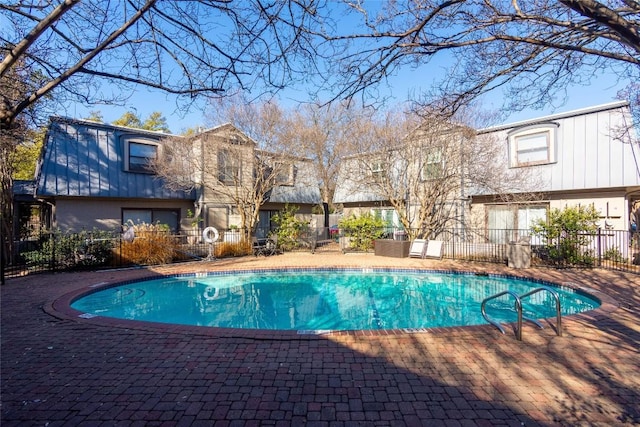 community pool with a patio area and fence