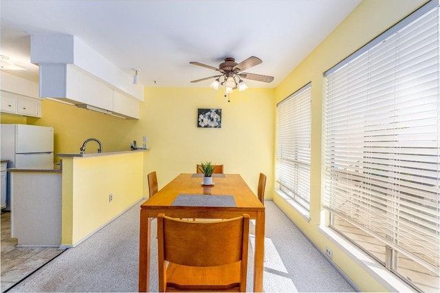 dining area featuring sink, light carpet, and ceiling fan