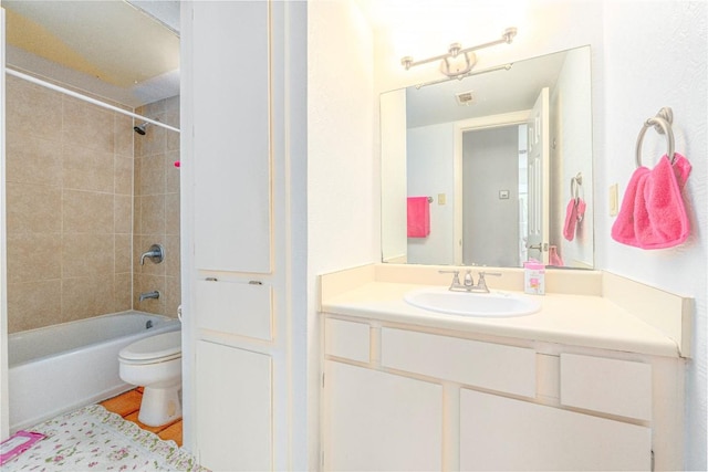 full bathroom featuring vanity, tiled shower / bath, and toilet