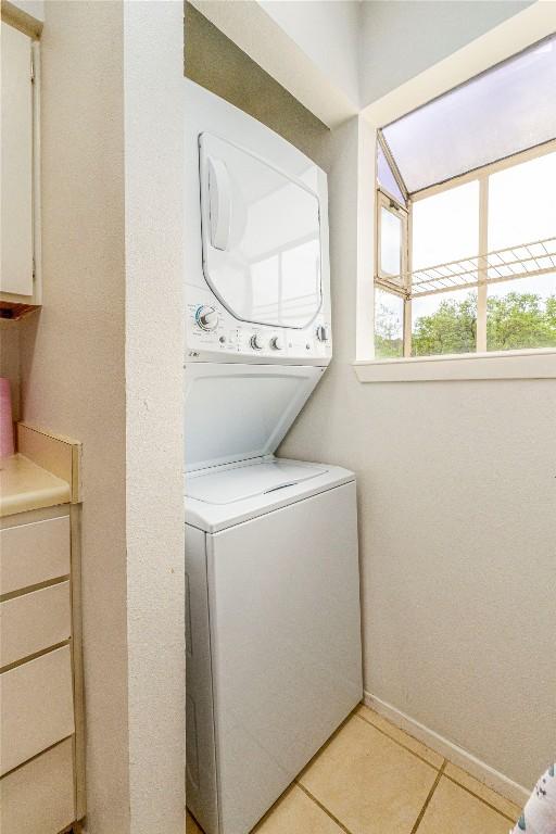 clothes washing area featuring stacked washing maching and dryer and light tile patterned floors