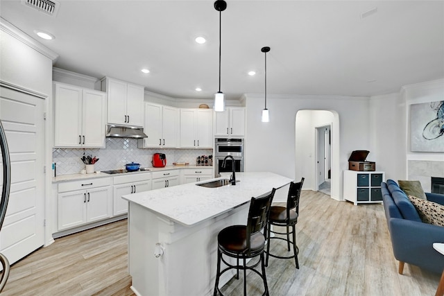 kitchen featuring sink, decorative light fixtures, stainless steel double oven, black electric stovetop, and white cabinets