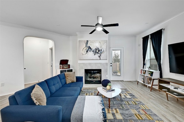 living room with light hardwood / wood-style flooring, a fireplace, ornamental molding, and ceiling fan