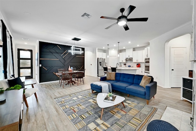 living room featuring ornamental molding, ceiling fan, and light wood-type flooring