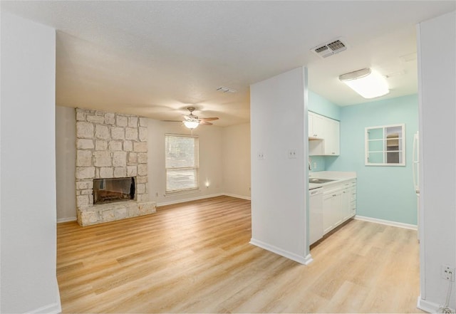 unfurnished living room with ceiling fan, sink, a fireplace, and light hardwood / wood-style flooring