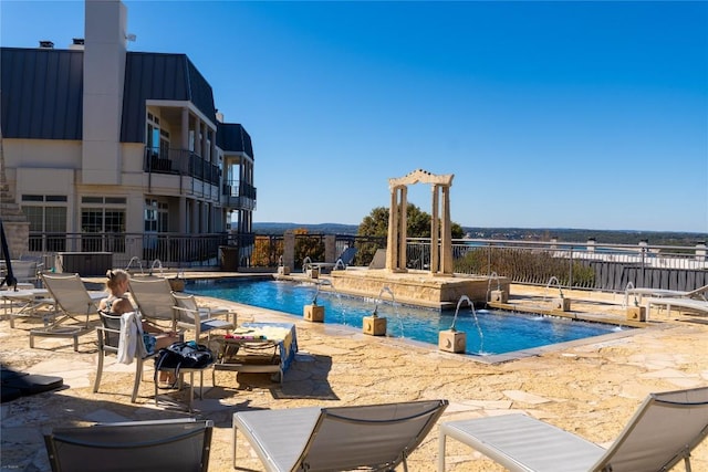 view of pool featuring a hot tub, pool water feature, and a patio area