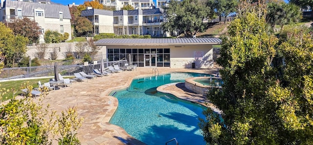 view of pool with a sunroom, a patio area, and a community hot tub