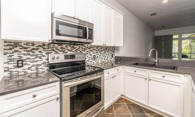 kitchen with white cabinetry, appliances with stainless steel finishes, sink, and decorative backsplash