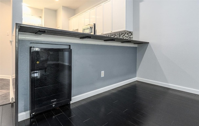 kitchen featuring white cabinetry, dark wood-type flooring, beverage cooler, and decorative backsplash