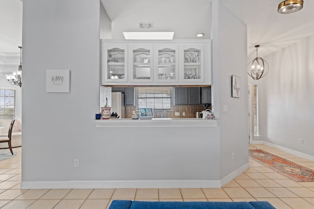 kitchen with an inviting chandelier, light tile patterned floors, a wealth of natural light, and white cabinets