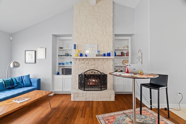 living room featuring vaulted ceiling, hardwood / wood-style floors, and built in features