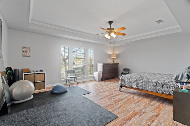 bedroom featuring crown molding, hardwood / wood-style flooring, a raised ceiling, and ceiling fan