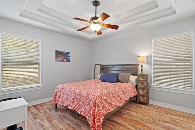 bedroom featuring a tray ceiling and light hardwood / wood-style flooring