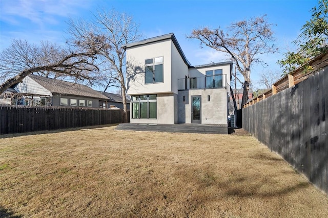 rear view of property with a balcony, a lawn, and a patio area