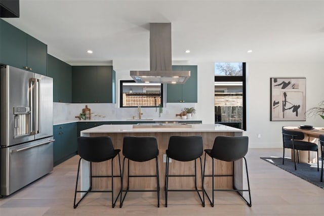 kitchen featuring a kitchen bar, sink, high end refrigerator, a kitchen island, and island exhaust hood