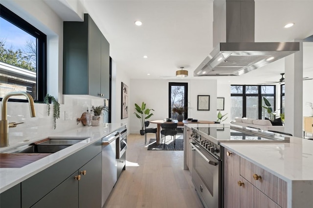 kitchen featuring island exhaust hood, appliances with stainless steel finishes, gray cabinets, and sink