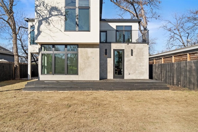 back of property featuring a balcony and a yard