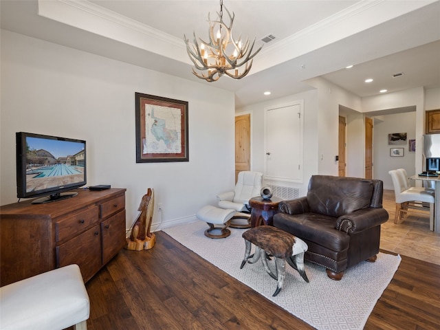 living room featuring a raised ceiling, crown molding, dark hardwood / wood-style floors, and an inviting chandelier