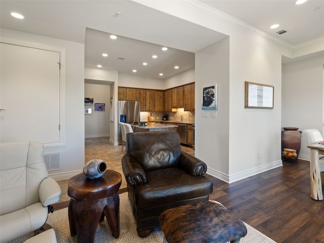 living room with dark wood-type flooring, ornamental molding, and sink