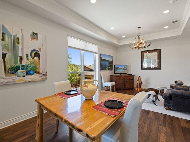 dining space featuring dark hardwood / wood-style flooring, crown molding, a raised ceiling, and an inviting chandelier